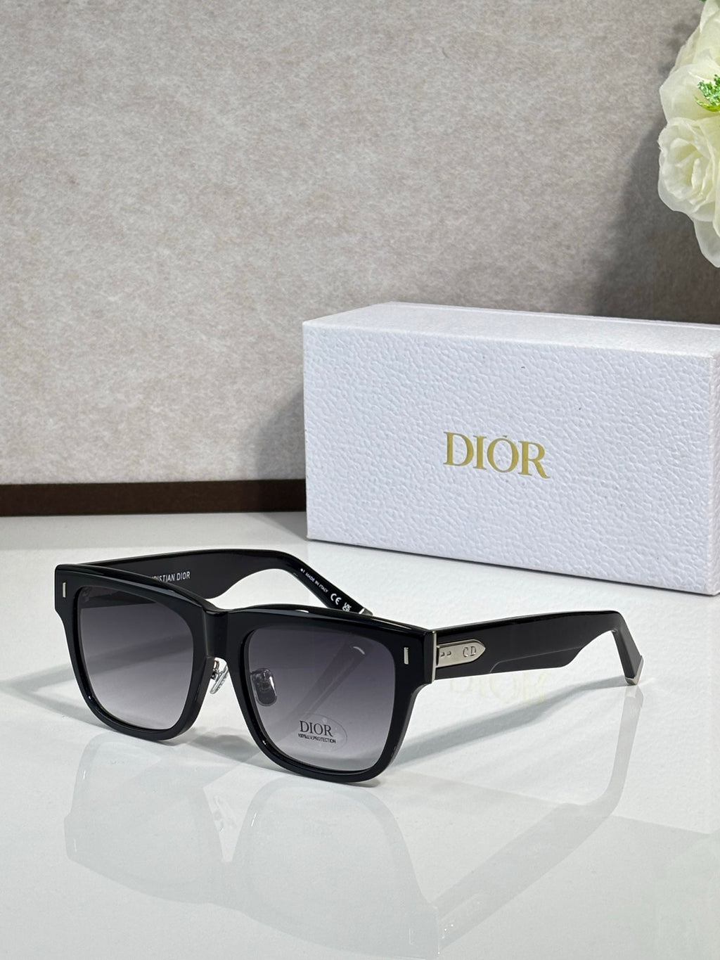 Dior sunglasses with black square frames and dark lenses, metal logo detail on temples
