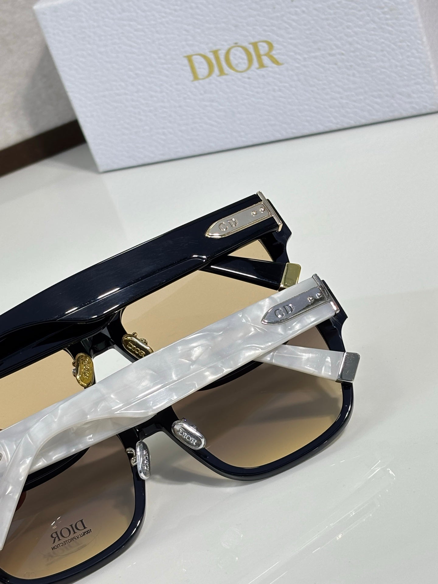 Dior sunglasses with black frames, clear temples, and gold-tone logo plates on side arms