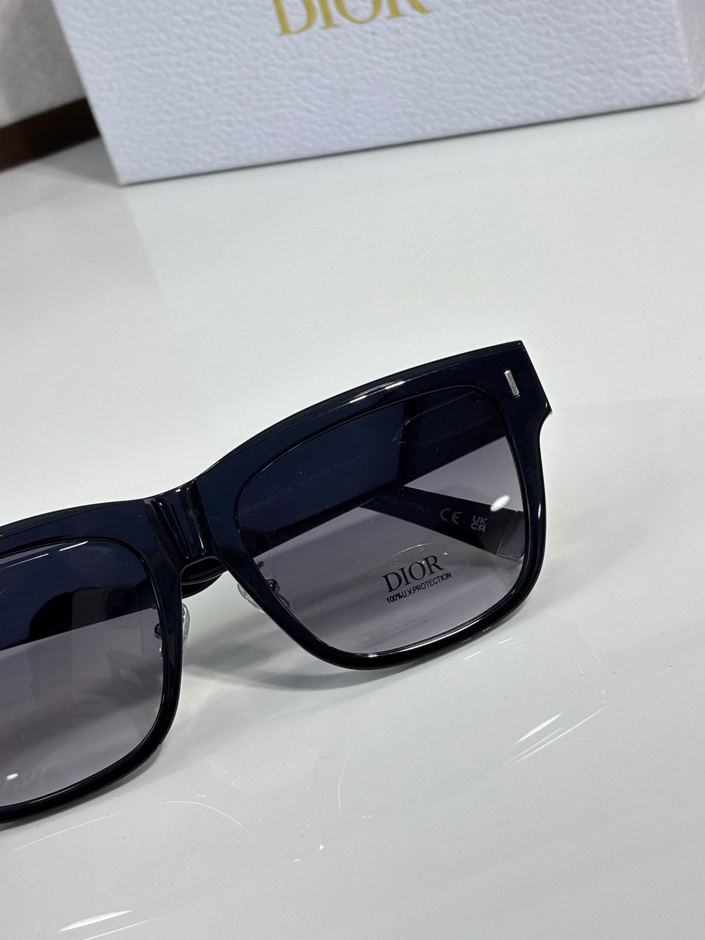 Dior sunglasses close-up with dark navy frames and tinted lenses, branding inside the lens