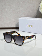 Dior sunglasses with tortoiseshell frames and dark lenses, gold logo accents on the sides