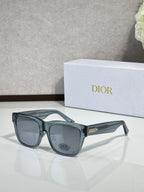 Dior sunglasses with dark teal frames and smoky lenses, gold-tone logo accents on temples