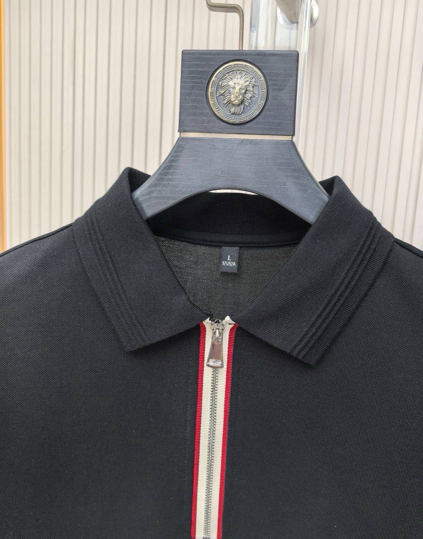 Black polo shirt collar with zip pull and vertical stripe trim.