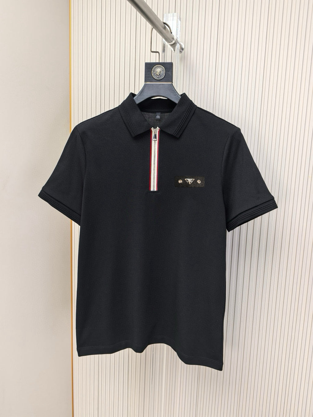 Black short-sleeve polo shirt with zip placket and small logo on chest.