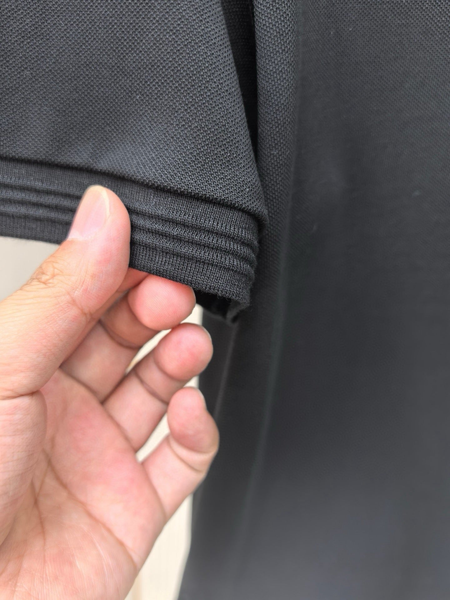 Black polo shirt sleeve cuff with ribbed trim detail.