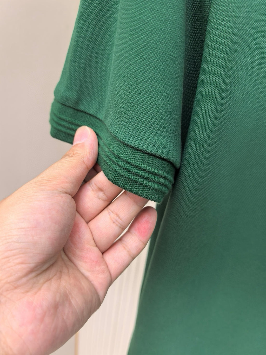 Prada polo shirt sleeve hem in dark green, hand holding cuff