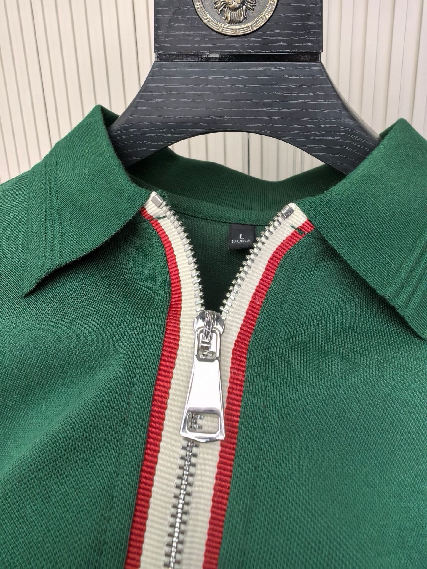 Half-zip placket with red-and-white striped tape on green polo