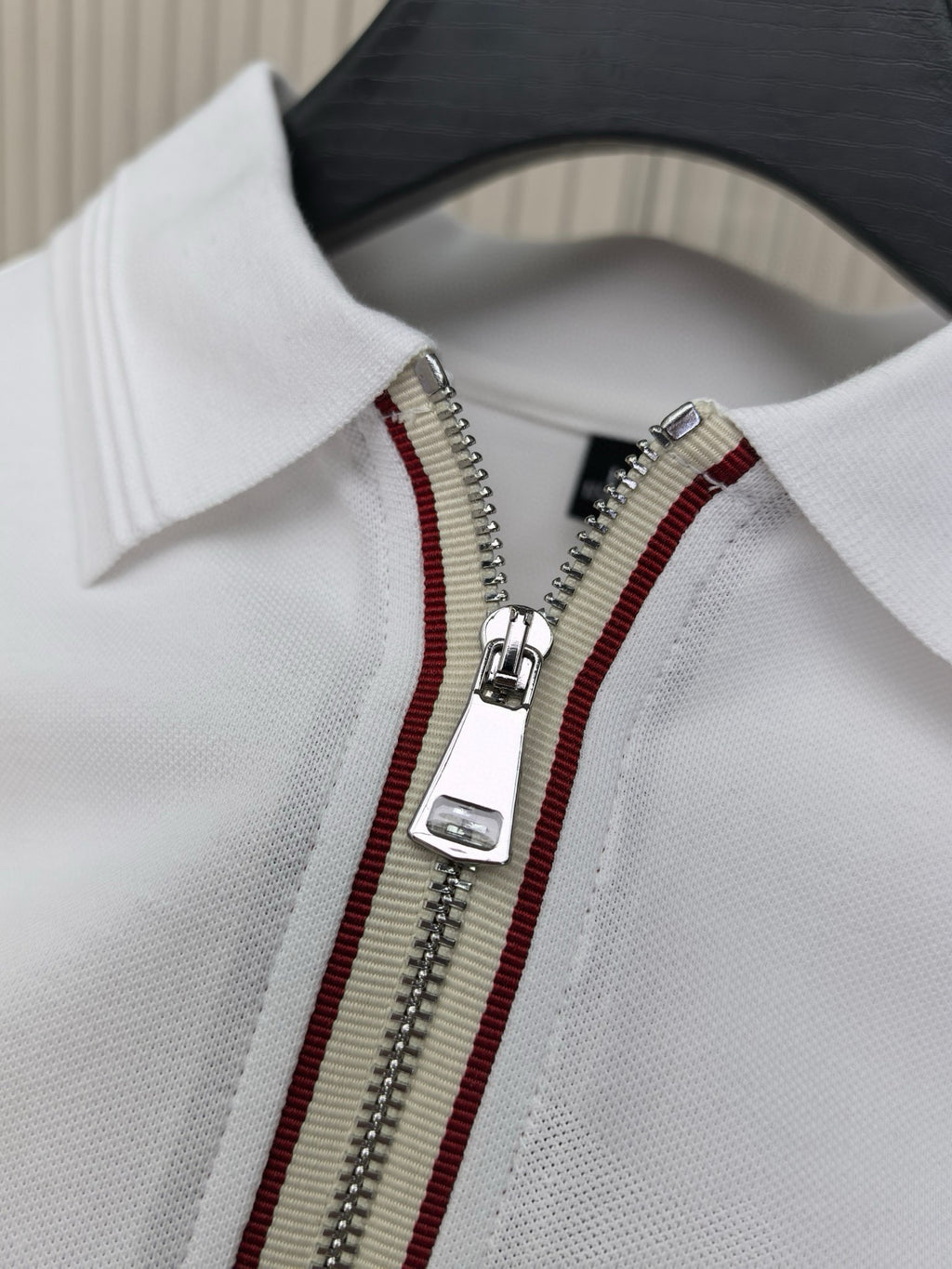 White polo shirt close-up of half-zip with red and gold trim