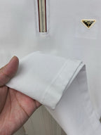 Sleeve cuff and hem of a white polo shirt, shown in hand