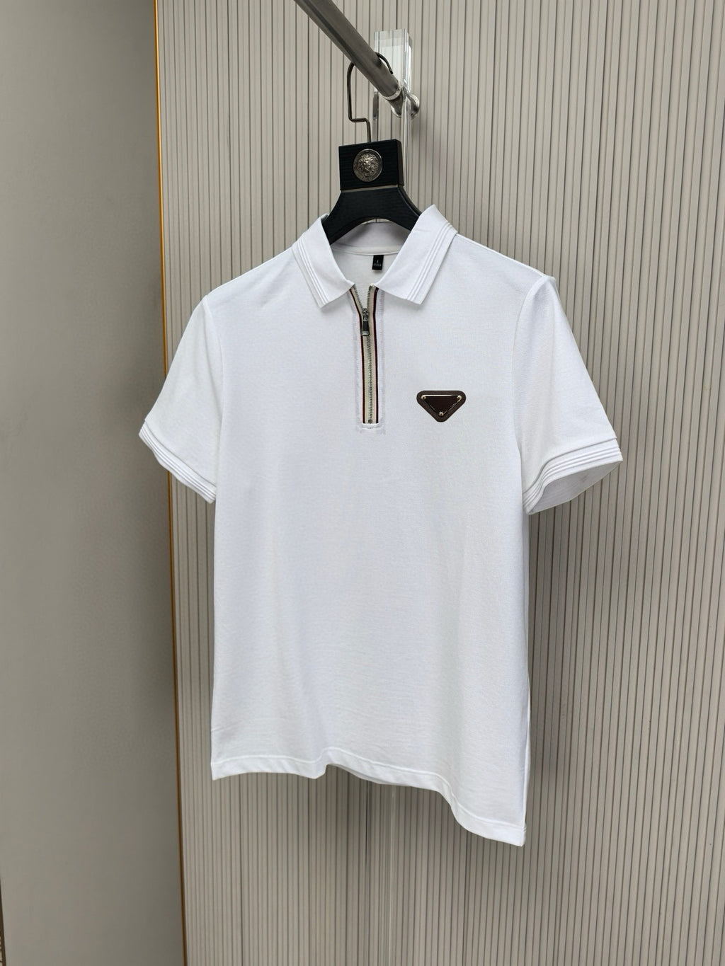 White polo shirt with stand collar, zip placket, and small triangular chest logo