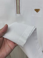 White polo shirt sleeve cuff and folded hem, held in a hand; ribbed knit detail.