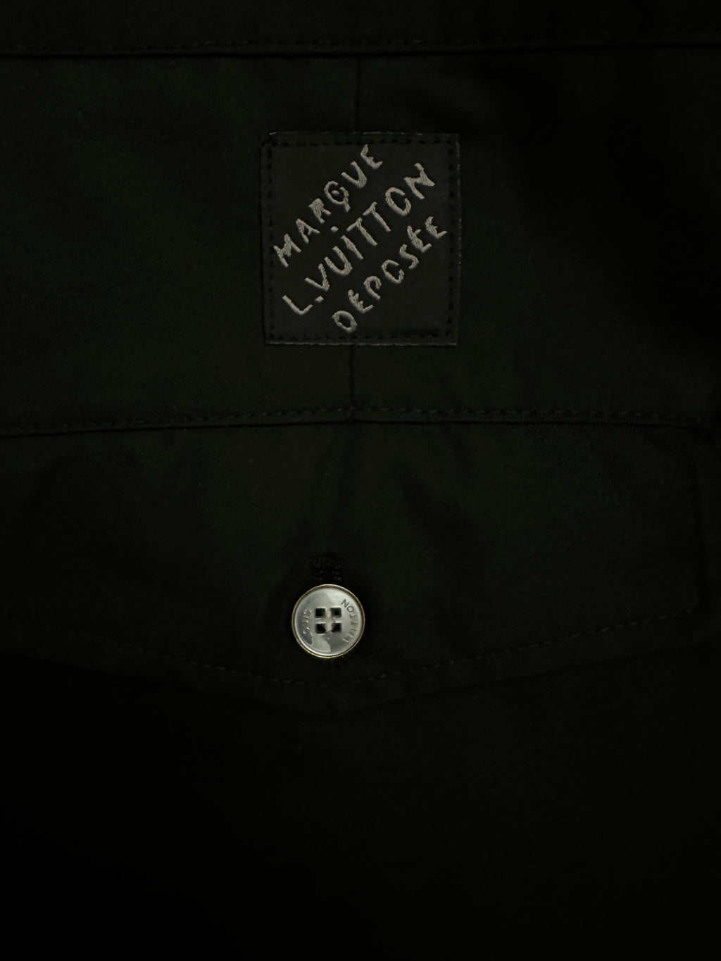 Black pants interior label patch with text and small metal button