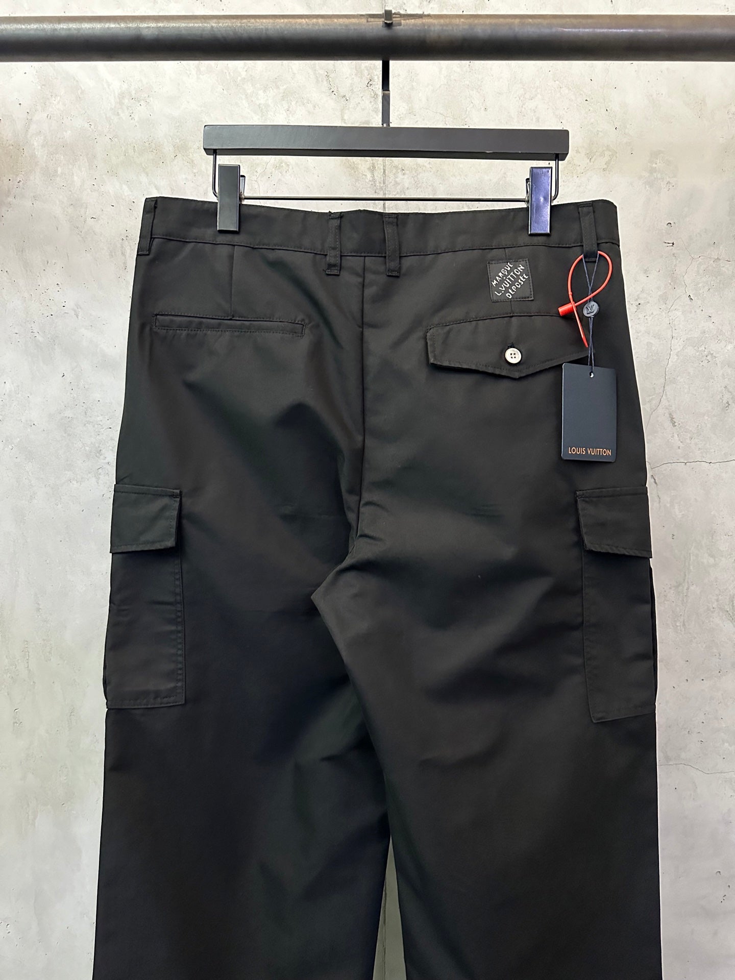 Black cargo pants back view with button pocket flap and hanging tag