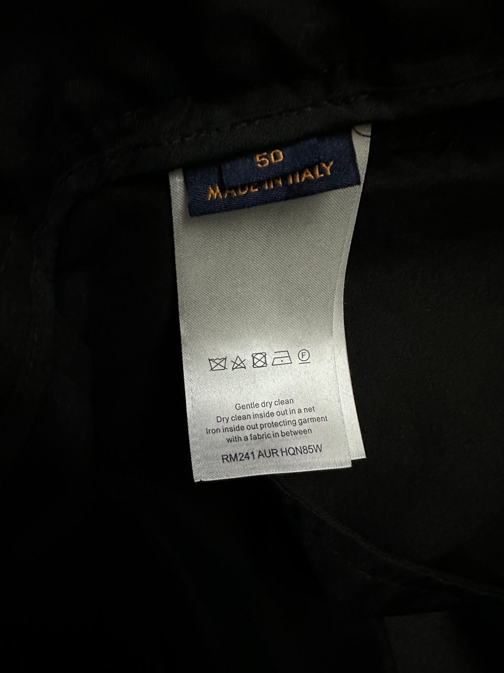 Black pants care and size tag showing “MADE IN ITALY” and “50”