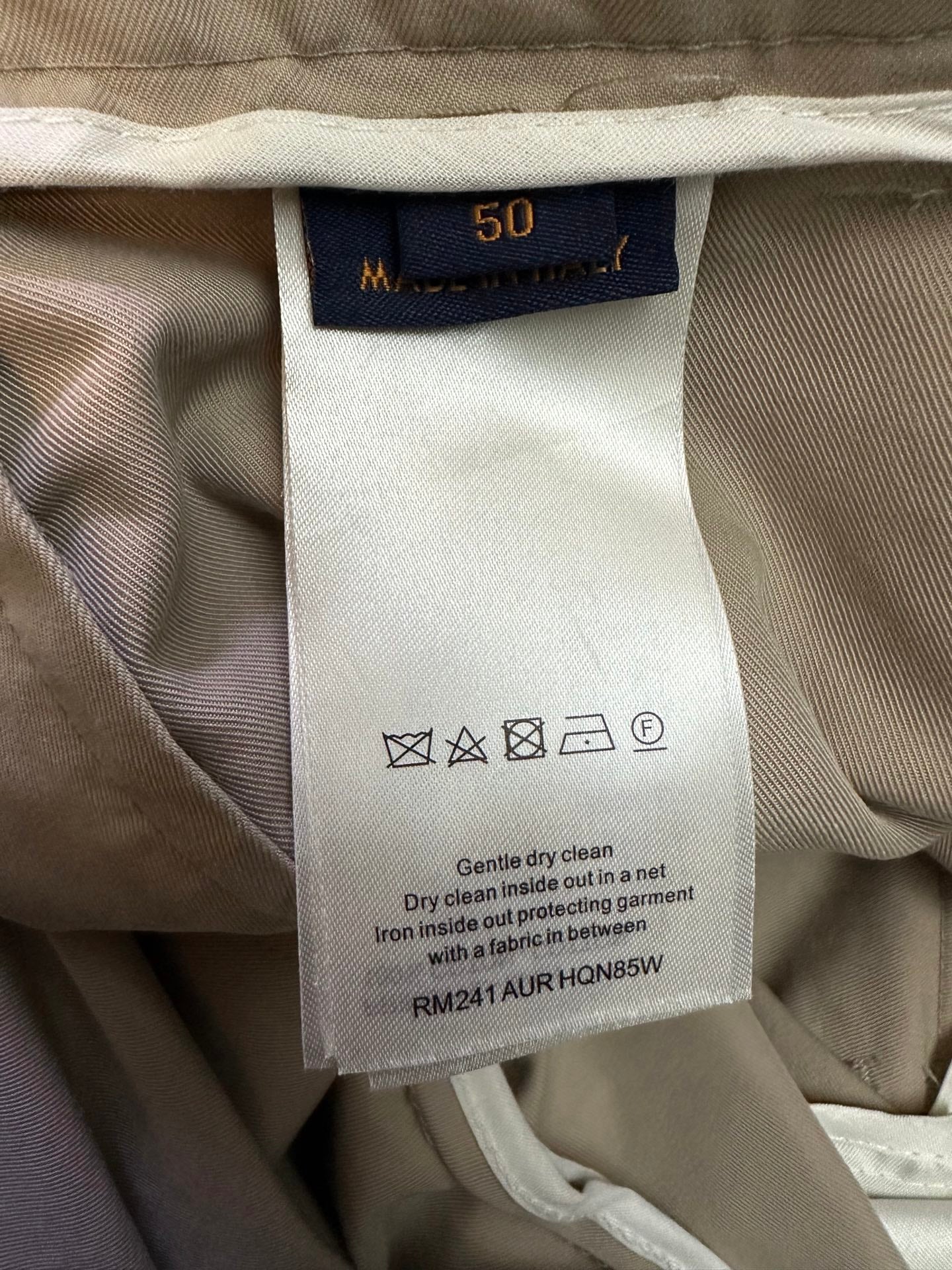 Beige pants care label with size 50 and wash instructions