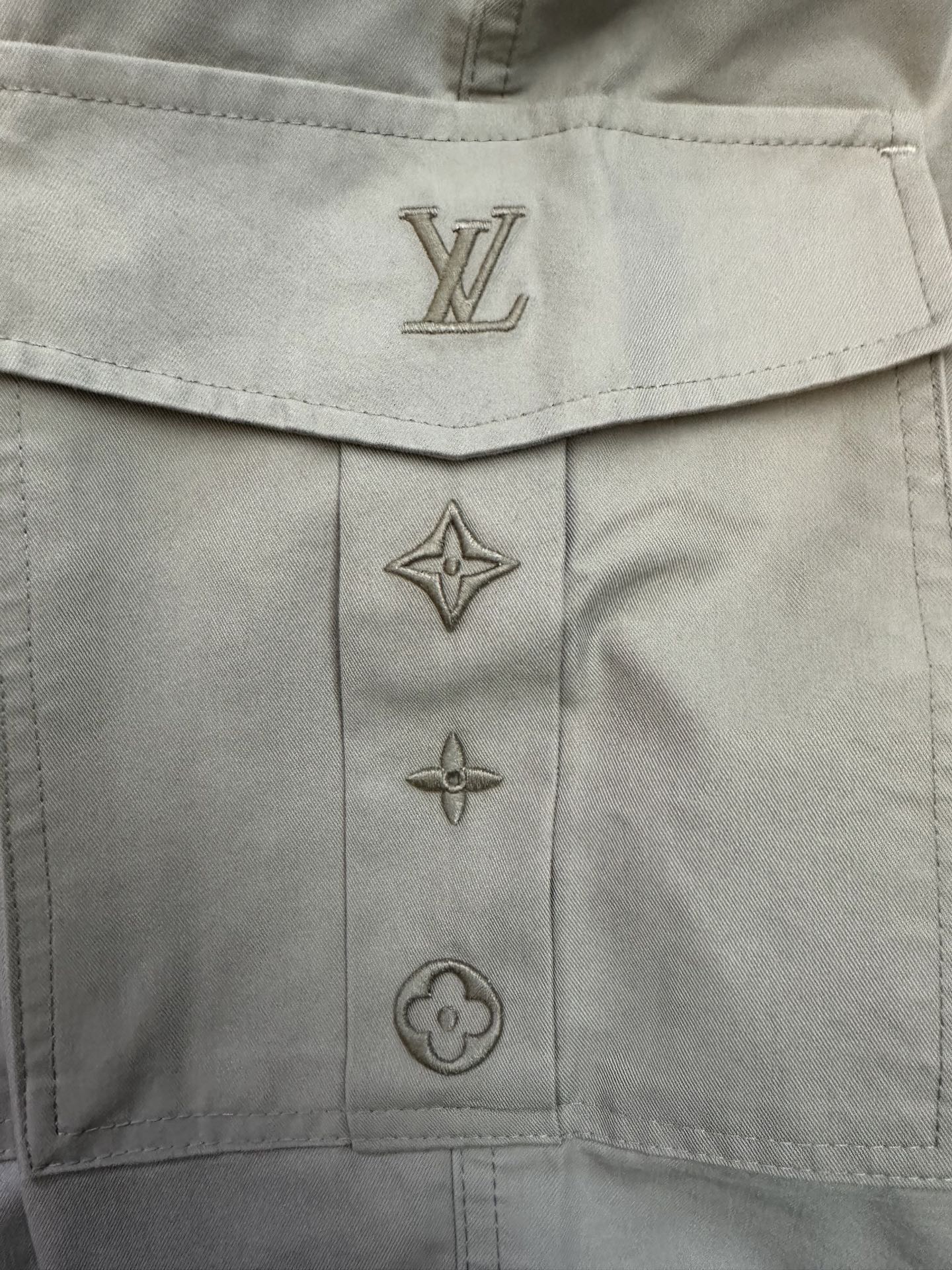 Beige pants button placket with Louis Vuitton monogram and star emblems