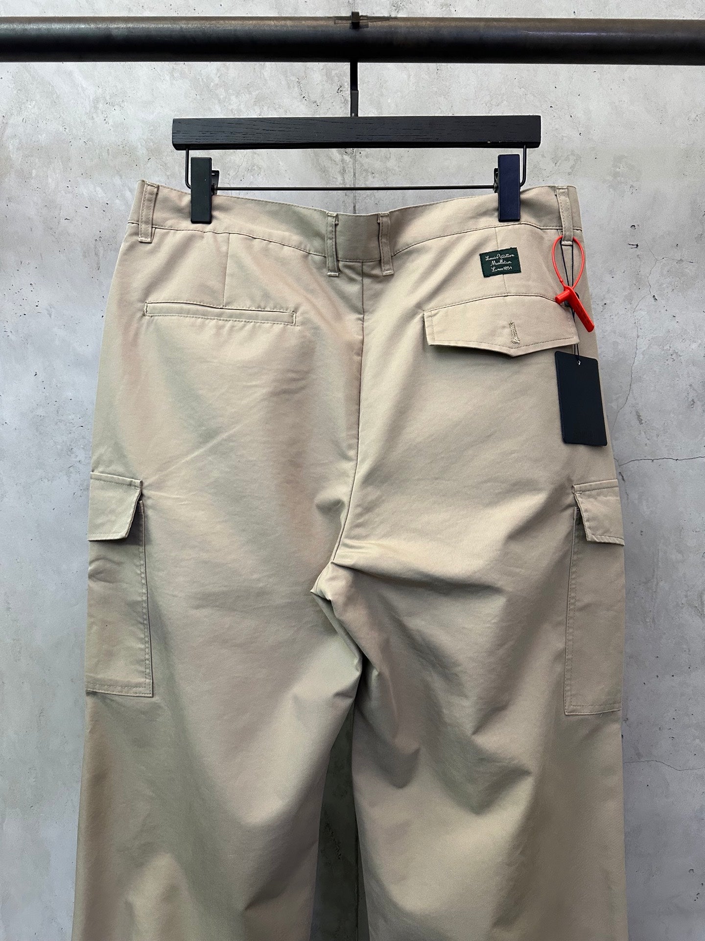 Beige cargo pants with front flap pocket and attached tag