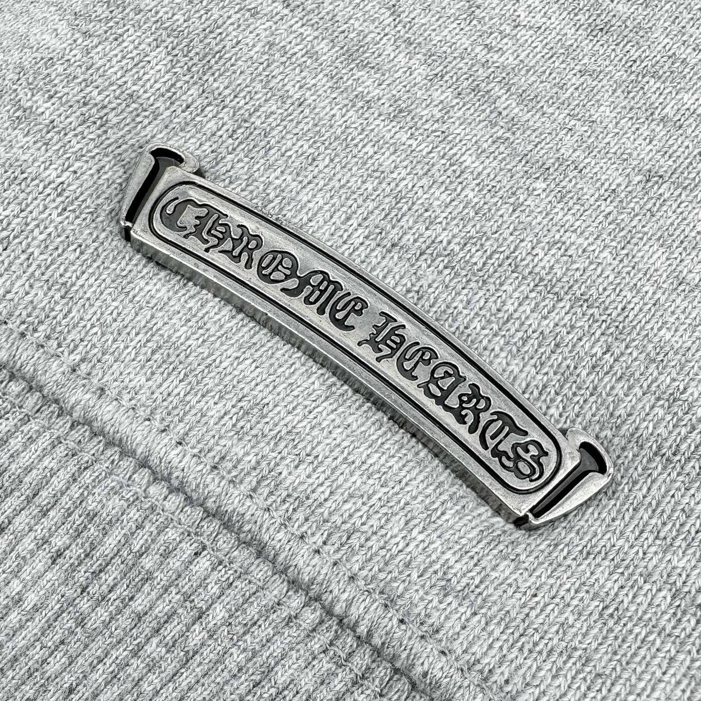 Chrome Hearts-branded metal neck label on heather gray sweatshirt seam