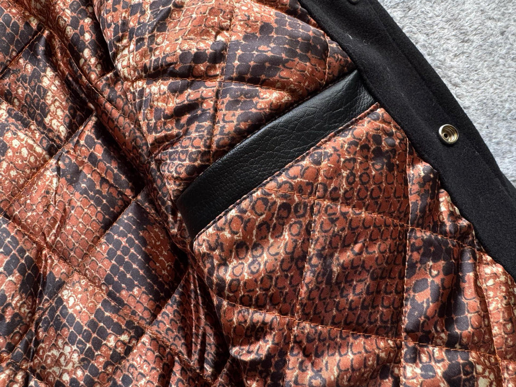 Snake-print quilted lining with black trim panel inside a black varsity jacket
