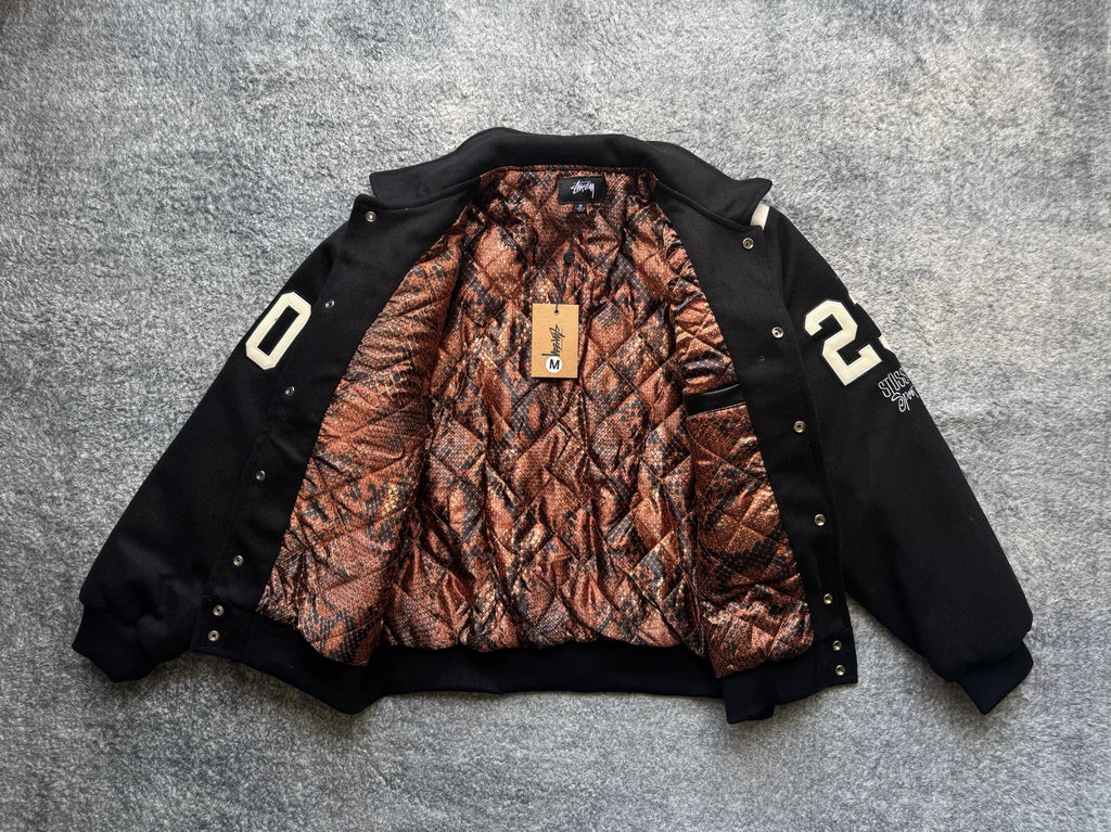 Black varsity jacket open front with orange-and-brown snake-print lining