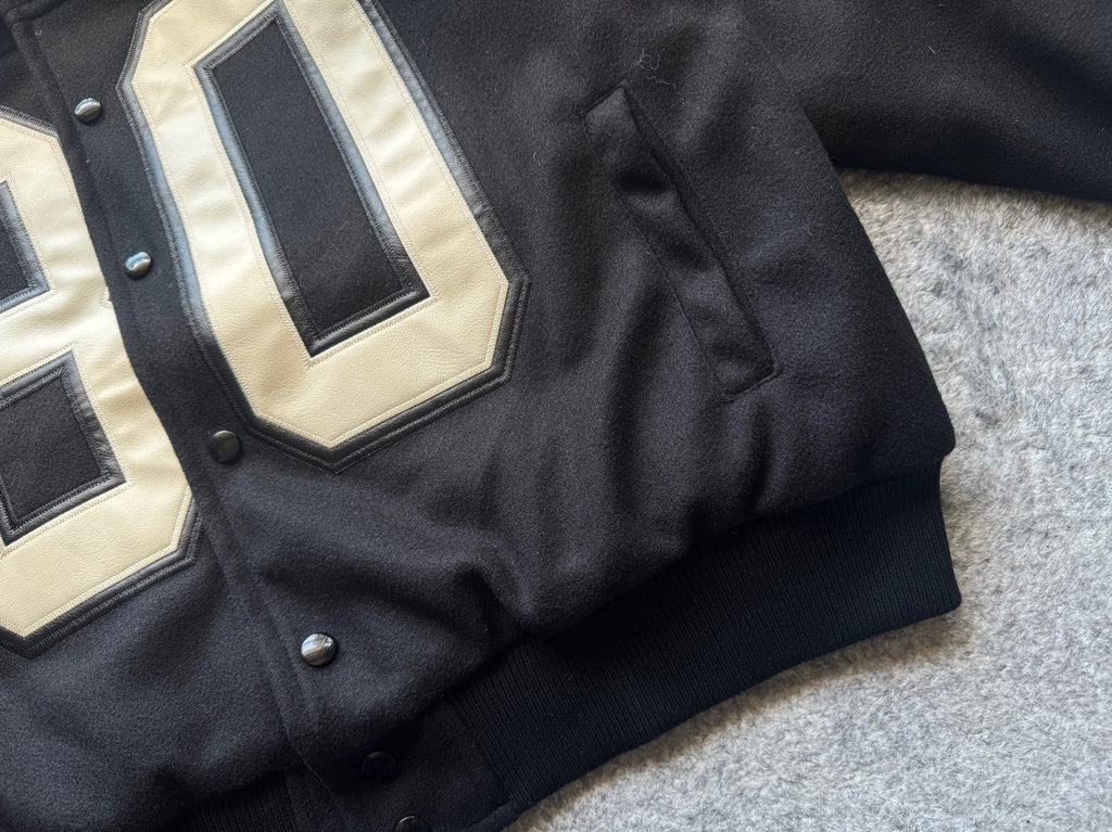 Black varsity jacket ribbed cuffs and snap buttons with partial “80” patch