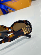 Tortoiseshell sunglasses close-up with gold LV emblem on side