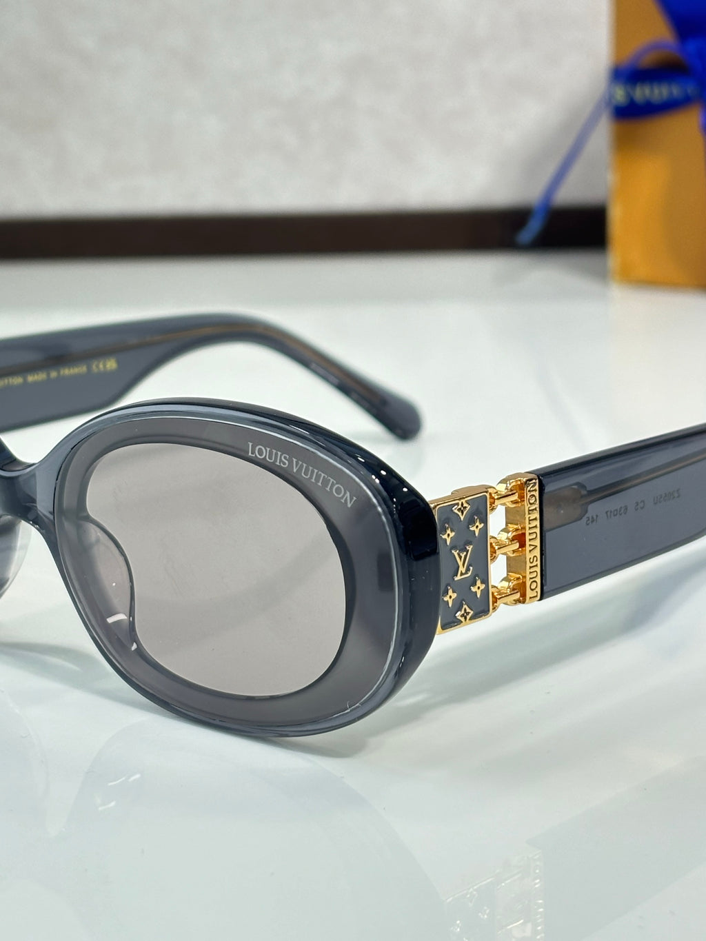 Black sunglasses close-up showing gold LV emblem on temple