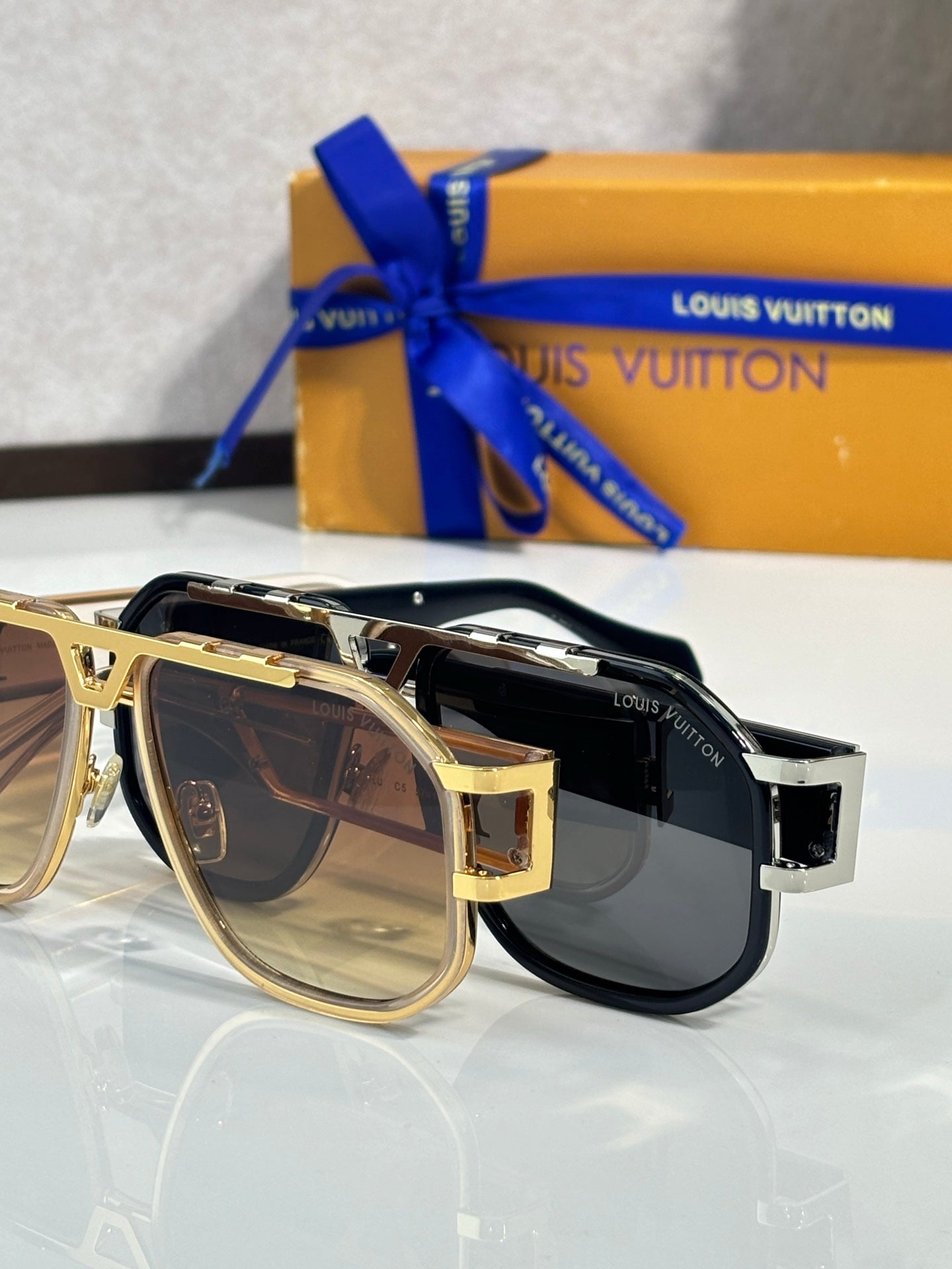 Louis Vuitton sunglasses in black and gold with dark lenses, close side view