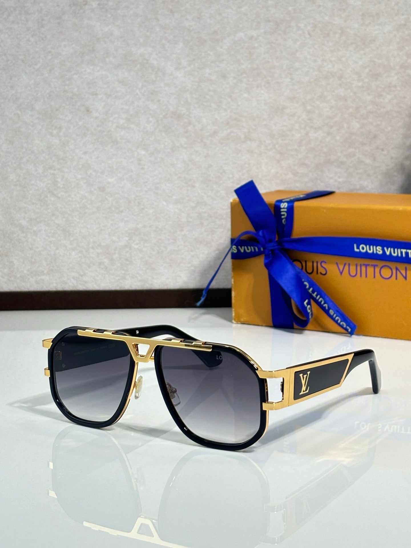 Louis Vuitton sunglasses with black frames, dark tinted lenses, gold trim on arms