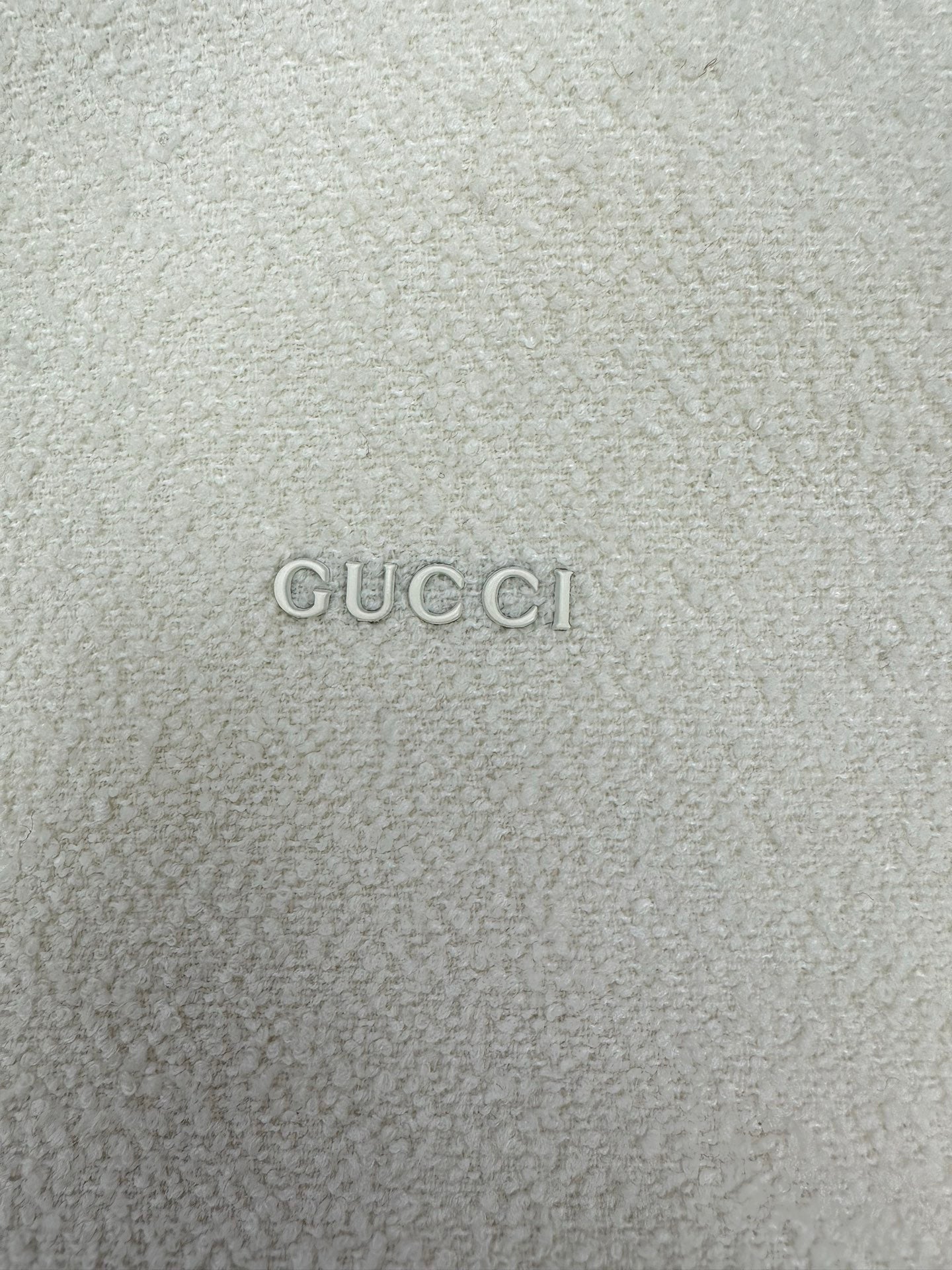 Off-white hoodie fabric with GUCCI logo text