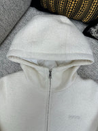 Off-white zip-up hoodie with hood and front zipper; small chest logo