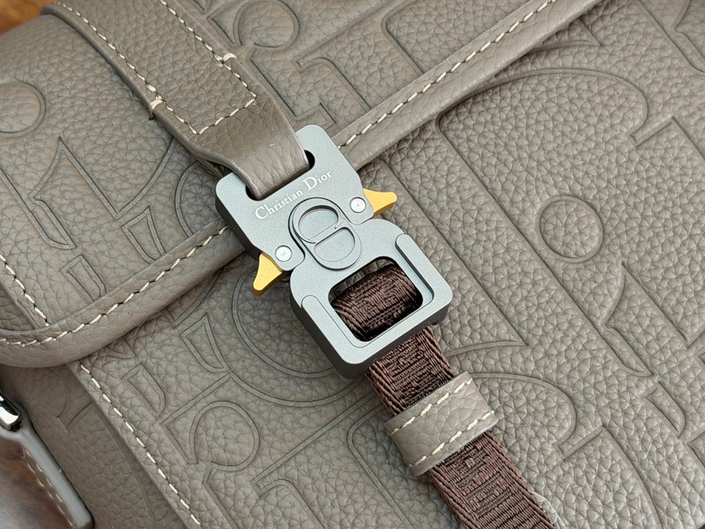 Dior bag keychain attachment on light gray strap hardware with brown webbing