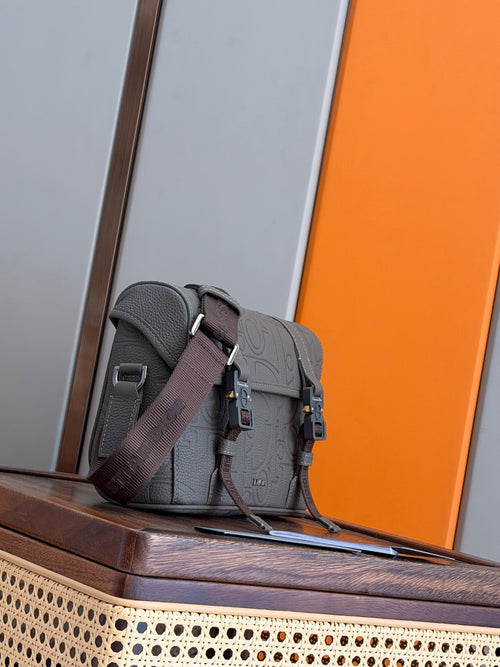 Dior men's messenger bag with textured logo pattern, dark strap, and front flap