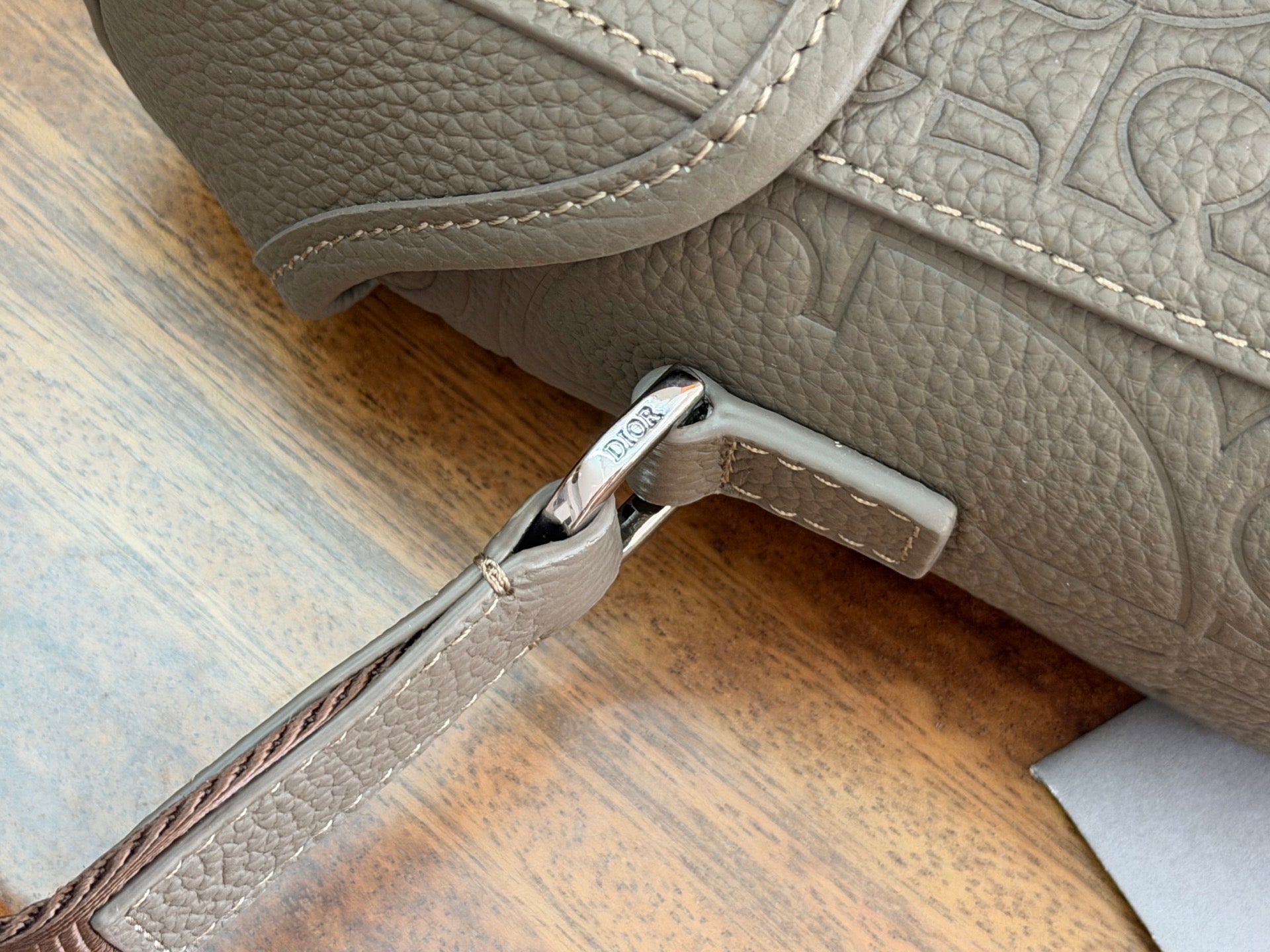 Dior bag side strap with silver buckle on light gray embossed leather