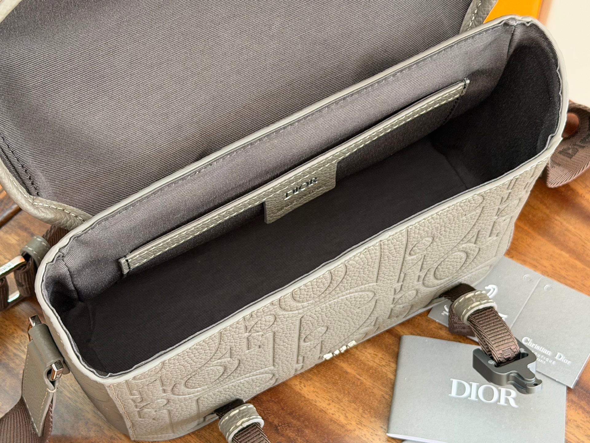 Dior men's bag interior view with dark lining and embossed logo base