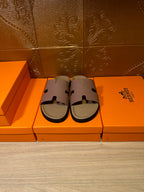 Hermes slide sandals pair on orange boxes, lilac straps and beige base