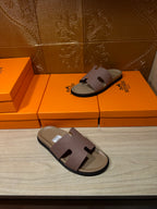 Hermes slide sandals with lilac straps and black trim, on the floor