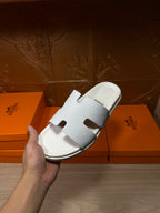 Hermes white slide sandal with textured band and open toe, side angle view