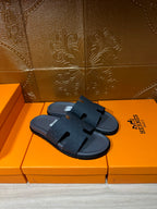 Dark blue slide sandal pair on orange shoeboxes, open toe with cross strap