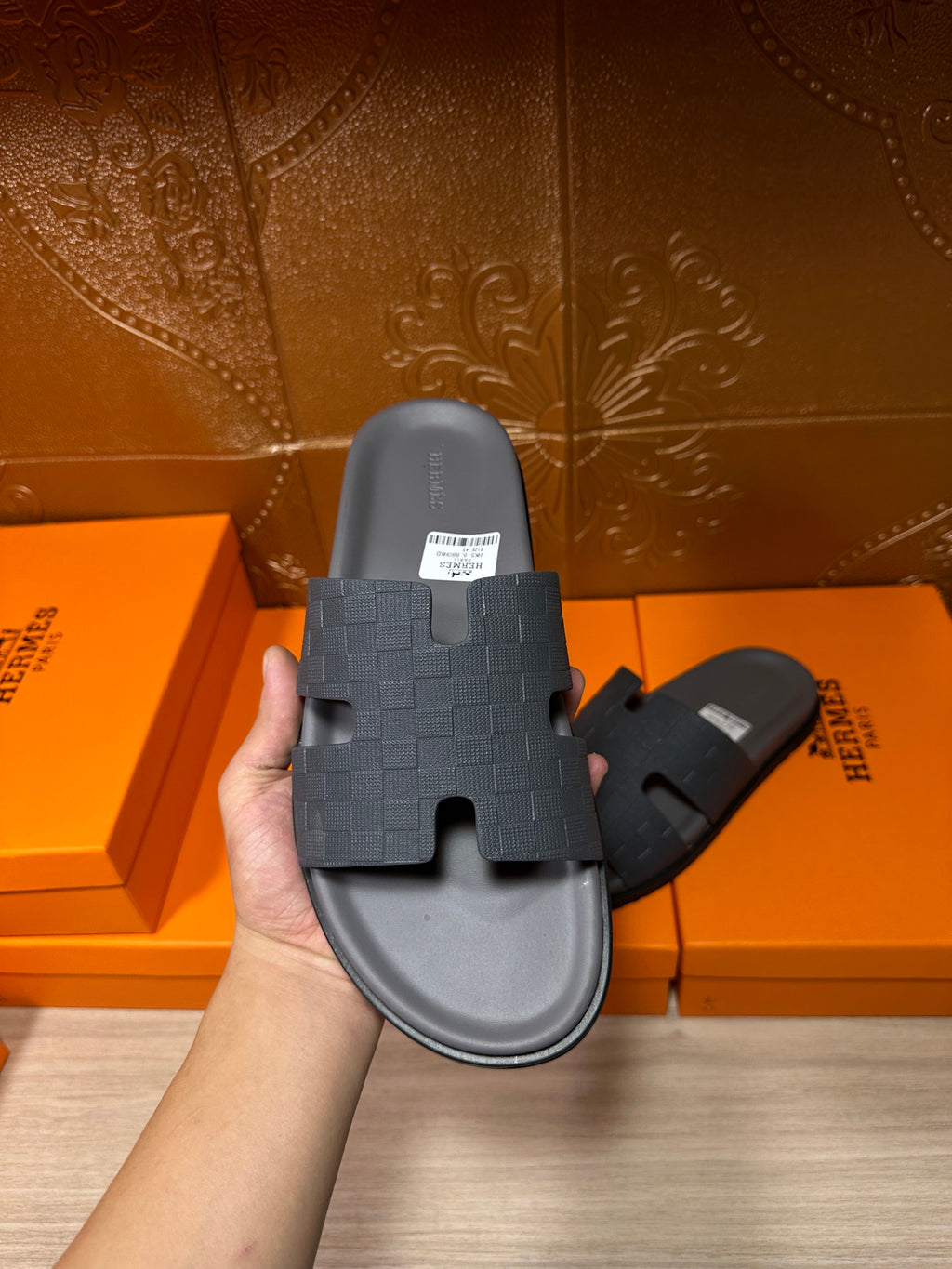 Hand holding dark blue slide sandal with textured cross strap and contoured sole