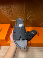 Hand holding dark blue slide sandal with textured cross strap and contoured sole