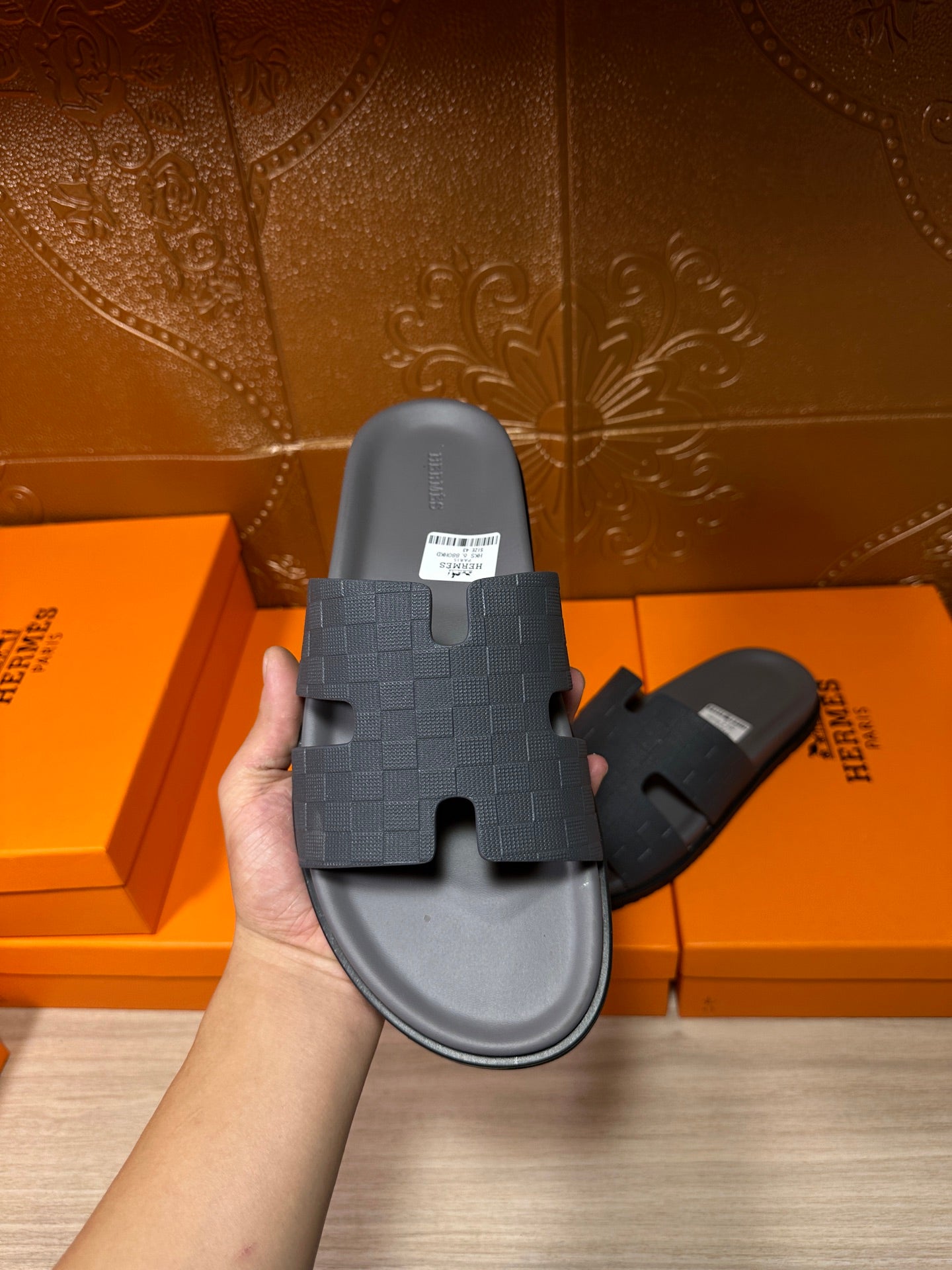 Hand holding dark blue slide sandal with textured cross strap and contoured sole