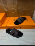 Hermes slide sandals with dark straps and cushioned black footbed, pair