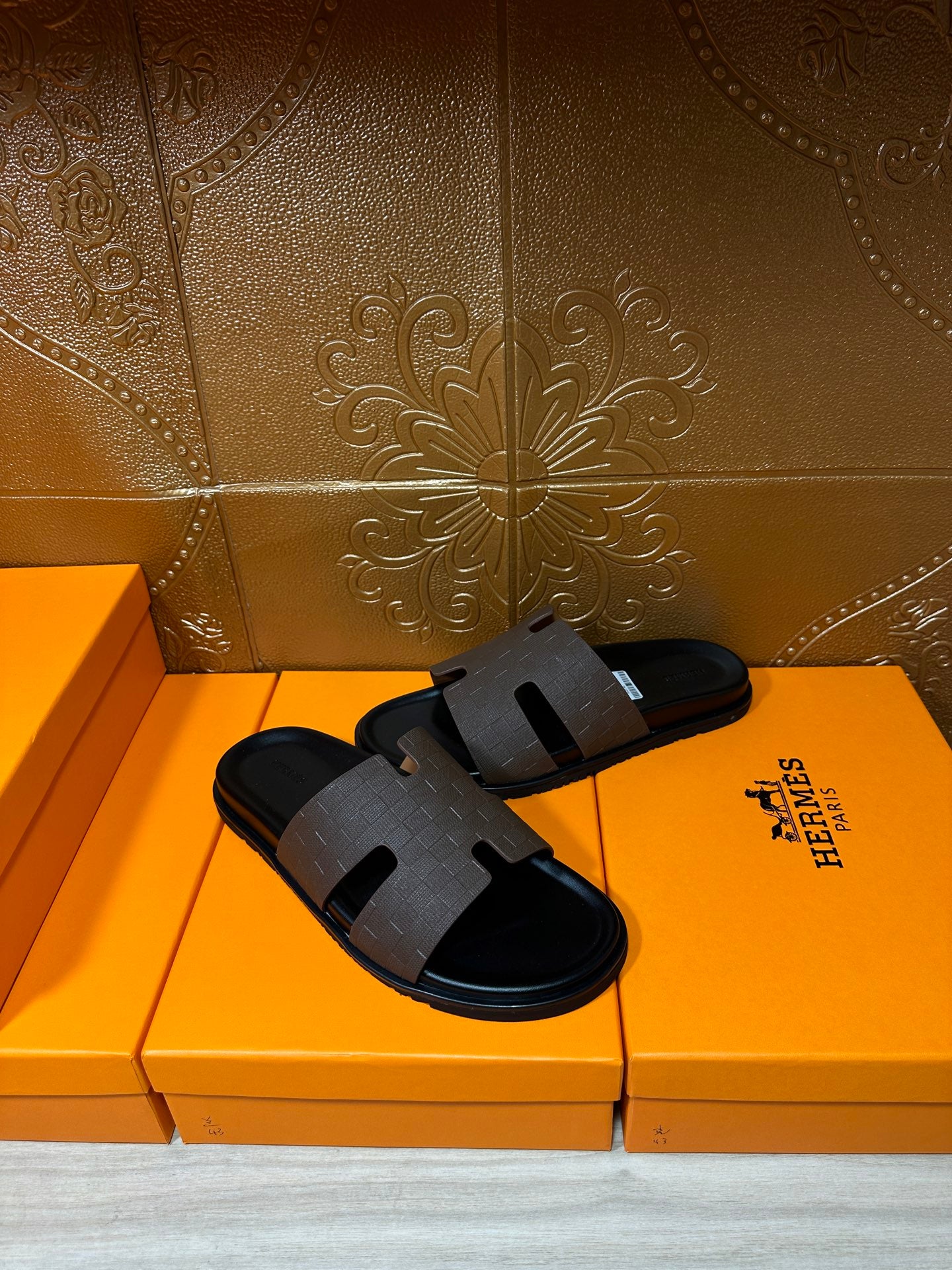 Hermes slide sandals with dark textured strap and open toe, angled view