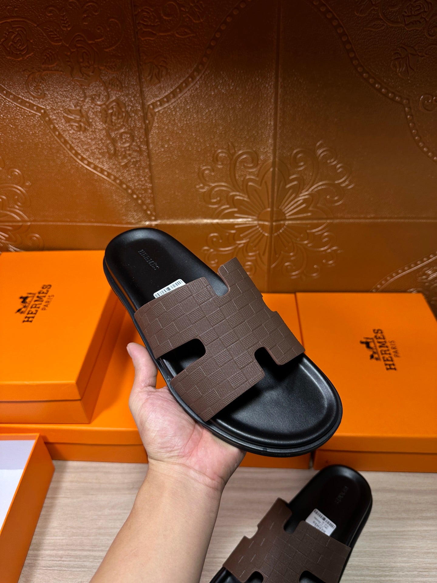 Hermes slide sandal held in hand, dark textured strap and open toe