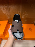 Hermes slide sandal held in hand with dark footbed and open toe