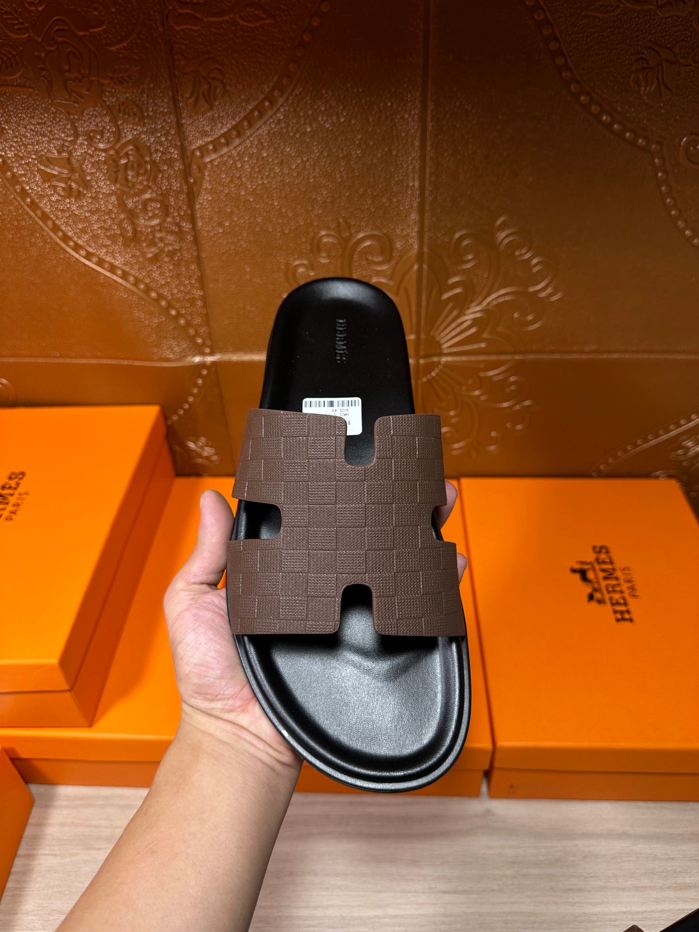 Hermes slide sandal held in hand with dark footbed and open toe