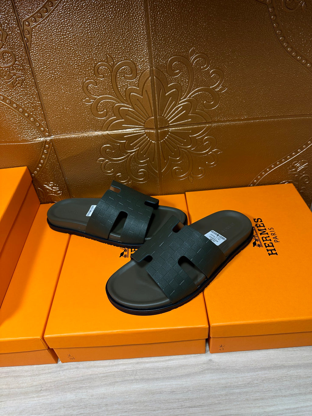 Hermes slide sandals, dark green thick strap and textured footbed, displayed on orange boxes