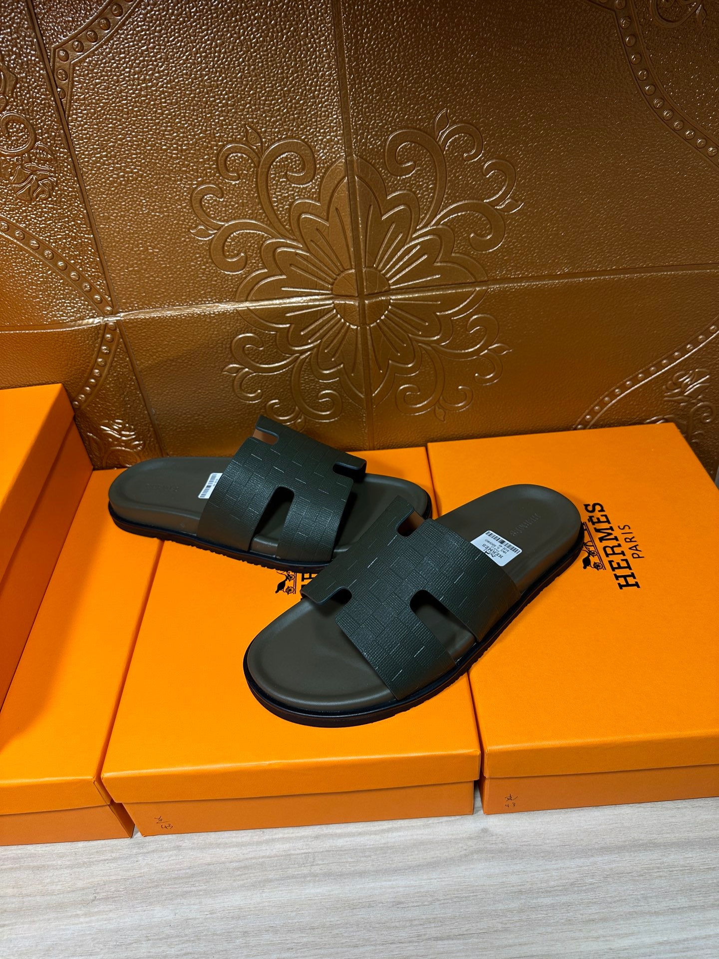 Hermes slide sandals, dark green thick strap and textured footbed, displayed on orange boxes