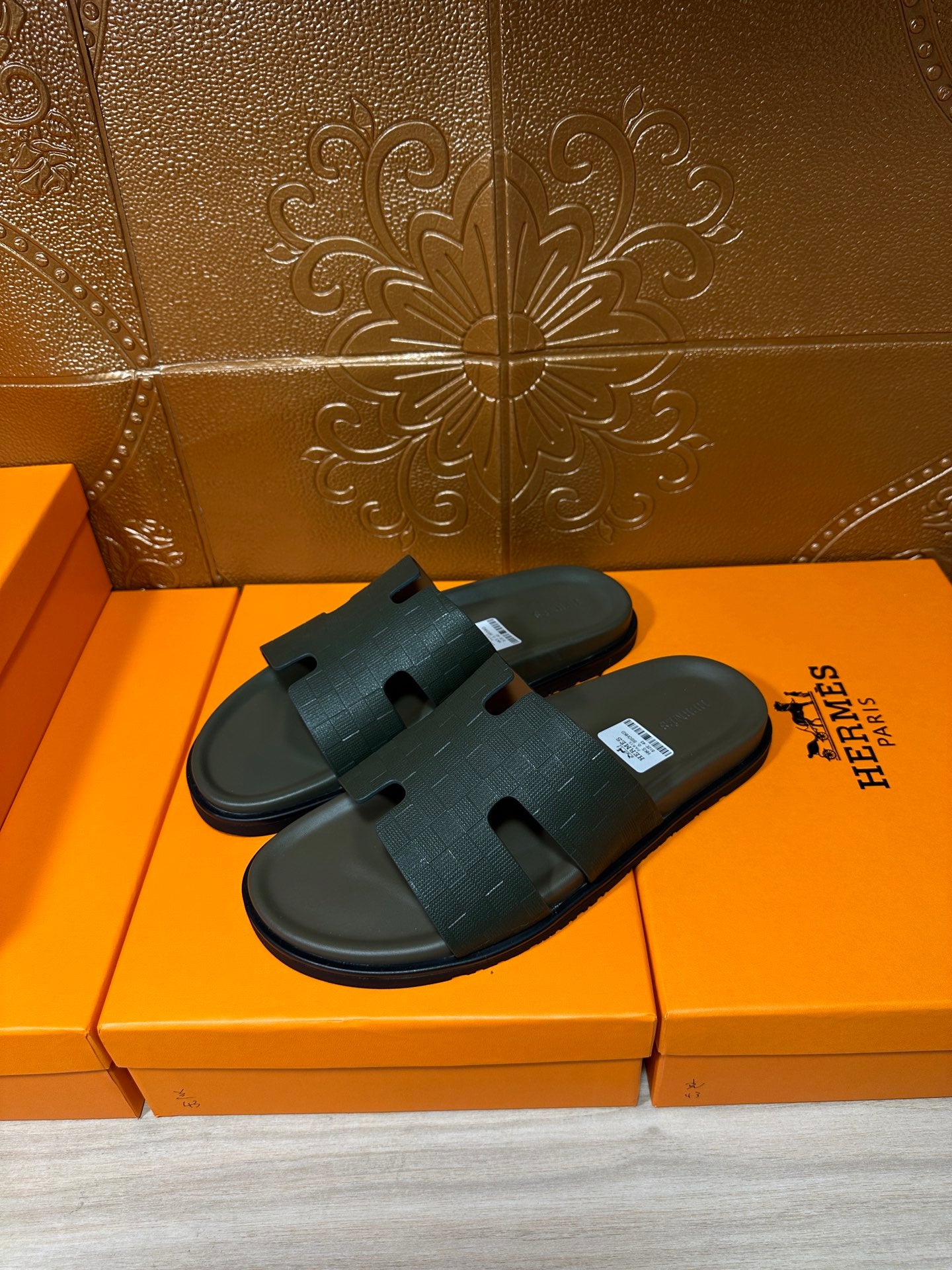 Hermes slide sandals, dark green with crossed wide strap, angled view on orange box