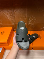 Hermes slide sandal, dark green sole side shown in hand, wide strap